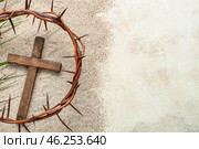 Wooden cross with crown of thorns and palm leaf on sand. Good Friday concept. Стоковое фото, фотограф Pixel_shot / Фотобанк Лори