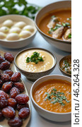 Iftar dinner table setting featuring various traditional dishes and dates. Стоковое AI-изображение, AI-художник Юрий Поздников / Фотобанк Лори