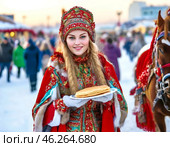 A beautiful girl in national dress treats with pancakes on Maslenitsa. Maslenitsa week. Стоковое AI-изображение, AI-художник Сергей Елизарьев / Фотобанк Лори