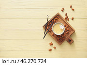 Board with tasty vanilla pudding in ramekin and almond on color wooden background. Стоковое фото, фотограф Pixel_shot / Фотобанк Лори