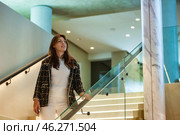 A stylish woman walks gracefully up a sleek staircase illuminated by soft lights. Her chic outfit and confident demeanor enhance the contemporary atmosphere of the sophisticated space. Стоковое фото, фотограф Aleksandr Golubev / Фотобанк Лори