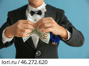 Cute little magician showing trick with money on color background, closeup. Стоковое фото, фотограф Pixel_shot / Фотобанк Лори