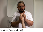 In a serene indoor setting, a skilled therapist provides a soothing foot massage to a client. Sunlight filters through, adding warmth to the tranquil atmosphere and promoting relaxation. Стоковое фото, фотограф Aleksandr Golubev / Фотобанк Лори