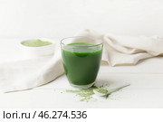 Glass with fresh wheatgrass juice and powder on light background. Стоковое фото, фотограф Pixel_shot / Фотобанк Лори