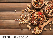 Various tasty nuts with bowls and spoon on wooden table. Стоковое фото, фотограф Pixel_shot / Фотобанк Лори