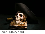 Human skull with old manuscripts, travel equipment, pirate hat and coins on black background. Стоковое фото, фотограф Pixel_shot / Фотобанк Лори