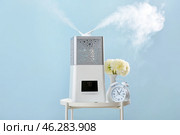 Modern humidifier, vase and alarm clock on table against color background. Стоковое фото, фотограф Pixel_shot / Фотобанк Лори