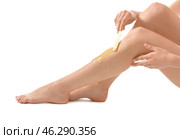 Young woman epilating her leg with liquid sugar on white background. Стоковое фото, фотограф Pixel_shot / Фотобанк Лори