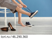 Tired young woman changing shoes indoors. Стоковое фото, фотограф Pixel_shot / Фотобанк Лори