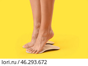 Female feet and orthopedic insoles on yellow background. Стоковое фото, фотограф Pixel_shot / Фотобанк Лори
