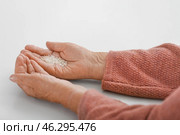 Hands of elderly woman with rice on white background. Concept of poverty. Стоковое фото, фотограф Pixel_shot / Фотобанк Лори