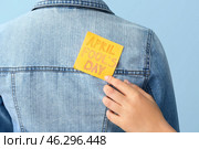 Woman sticking paper to her friend's back against color background, closeup. April Fools' Day prank. Стоковое фото, фотограф Pixel_shot / Фотобанк Лори
