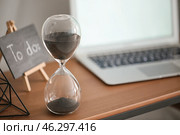 Hourglass with laptop on table in office. Time management concept. Стоковое фото, фотограф Pixel_shot / Фотобанк Лори