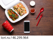 Flat lay composition with smartphone and takeout meal on wooden background. Food delivery. Стоковое фото, фотограф Pixel_shot / Фотобанк Лори