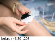 Female hands carefully peel off the protective film from an electrode of a muscle stimulator, preparing for use. Focus on the process of applying the device for muscle therapy. Стоковое фото, фотограф Татьяна Степанищева / Фотобанк Лори