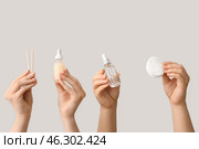 Female hands holding bottles of cuticle oil with orange sticks and cotton pads on white background. Стоковое фото, фотограф Pixel_shot / Фотобанк Лори