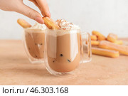 Woman decorating glass cup of tasty Tiramisu Latte with savoiardi on table. Стоковое фото, фотограф Pixel_shot / Фотобанк Лори