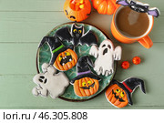 Plate with tasty cookies, candy corns and cup of coffee for Halloween celebration on color wooden background. Стоковое фото, фотограф Pixel_shot / Фотобанк Лори