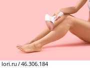Beautiful young woman epilating her legs with modern photoepilator on pink background. Стоковое фото, фотограф Pixel_shot / Фотобанк Лори