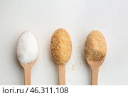 Different granulated sugar in wooden spoons on white background. Стоковое фото, фотограф Pixel_shot / Фотобанк Лори