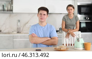 Aggrieved disheartened young guy, facing problems in relationships, sitting at kitchen table while dissatisfied girlfriend scolding him on blurred background. Стоковое видео, видеограф Яков Филимонов / Фотобанк Лори