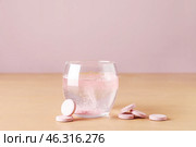 Glass of water with soluble tablets on beige table. Стоковое фото, фотограф Pixel_shot / Фотобанк Лори