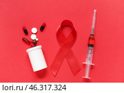 Red ribbon with pill bottle and syringe on color background. AIDS Day concept. Стоковое фото, фотограф Pixel_shot / Фотобанк Лори