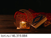 Arabic candle holder with glowing candle, Quran and carpet on dark background. Стоковое фото, фотограф Pixel_shot / Фотобанк Лори