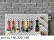 Pegboard with decorator's tools on grey brick wall, closeup. Стоковое фото, фотограф Pixel_shot / Фотобанк Лори