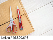 Utility knife with scissors on cardboard box, closeup. Стоковое фото, фотограф Pixel_shot / Фотобанк Лори