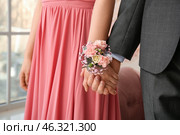 Young woman with corsage and her prom date holding hands, closeup. Стоковое фото, фотограф Pixel_shot / Фотобанк Лори