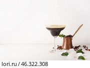 Glass of tasty espresso martini cocktail and jezve on light background. Стоковое фото, фотограф Pixel_shot / Фотобанк Лори