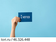 Hand holding paper with text I VOTED on color background. Стоковое фото, фотограф Pixel_shot / Фотобанк Лори