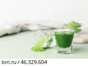 Glass with fresh wheatgrass juice and powder on color wooden background. Стоковое фото, фотограф Pixel_shot / Фотобанк Лори