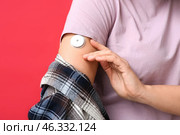 Woman with glucose sensor for measuring blood sugar level on red background, closeup. Diabetes concept. Стоковое фото, фотограф Pixel_shot / Фотобанк Лори