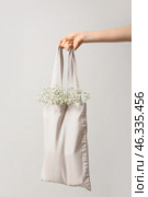 Female hand with flowers in eco bag on light background. Стоковое фото, фотограф Pixel_shot / Фотобанк Лори