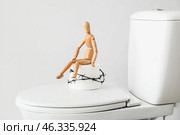 Toilet bowl with roll of paper, barbed wire and wooden human figure on light background. Hemorrhoids concept. Стоковое фото, фотограф Pixel_shot / Фотобанк Лори
