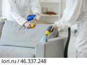 Workers in biohazard costume removing dirt from sofa in house. Стоковое фото, фотограф Pixel_shot / Фотобанк Лори
