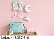 Bottles of milk for baby with pacifiers and clothes on chest of drawers. Стоковое фото, фотограф Pixel_shot / Фотобанк Лори