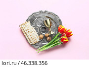 Passover Seder plate, flatbread matza, walnuts, flowers and cup on pink background. Стоковое фото, фотограф Pixel_shot / Фотобанк Лори