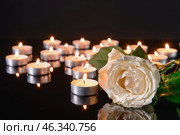 Many burning candles as symbol of mourning and flower on dark background. Стоковое фото, фотограф Pixel_shot / Фотобанк Лори
