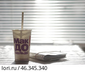Cold drink glass McDonald's with straw cocktail in light morning sun through blinds, big disposable cup with McDonalds restaurant logo isolated on white background, copy space: Gomel, Belarus - 2022 (2021 год). Редакционное фото, фотограф Дмитрий Нечаев / Фотобанк Лори