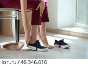 Tired young woman changing shoes indoors. Стоковое фото, фотограф Pixel_shot / Фотобанк Лори