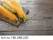 Board with tasty corncobs on wooden table. Стоковое фото, фотограф Pixel_shot / Фотобанк Лори