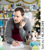 Middle-aged man restocking using paper in store with New Year decoration. Стоковое фото, фотограф Яков Филимонов / Фотобанк Лори