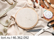 Embroidery hoop with canvas, mouline threads and scissors on brown wooden background. Стоковое фото, фотограф Pixel_shot / Фотобанк Лори