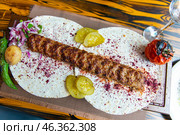 Traditional Caucasian appetizing kebab served with pickled cucumbers, stewed tomato and hot peppers on thin pita bread with fresh onion and spices. Стоковое фото, фотограф Евгений Ткачёв / Фотобанк Лори