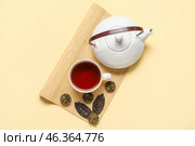 Bamboo mat with dry pressed puer tea, cup and teapot on beige background. Стоковое фото, фотограф Pixel_shot / Фотобанк Лори
