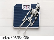 Scales and skeleton on white wooden background. Anorexia concept. Стоковое фото, фотограф Pixel_shot / Фотобанк Лори