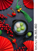 Bowl of tangyuan and Chinese decor on dark background. Dongzhi Festival. Стоковое фото, фотограф Pixel_shot / Фотобанк Лори